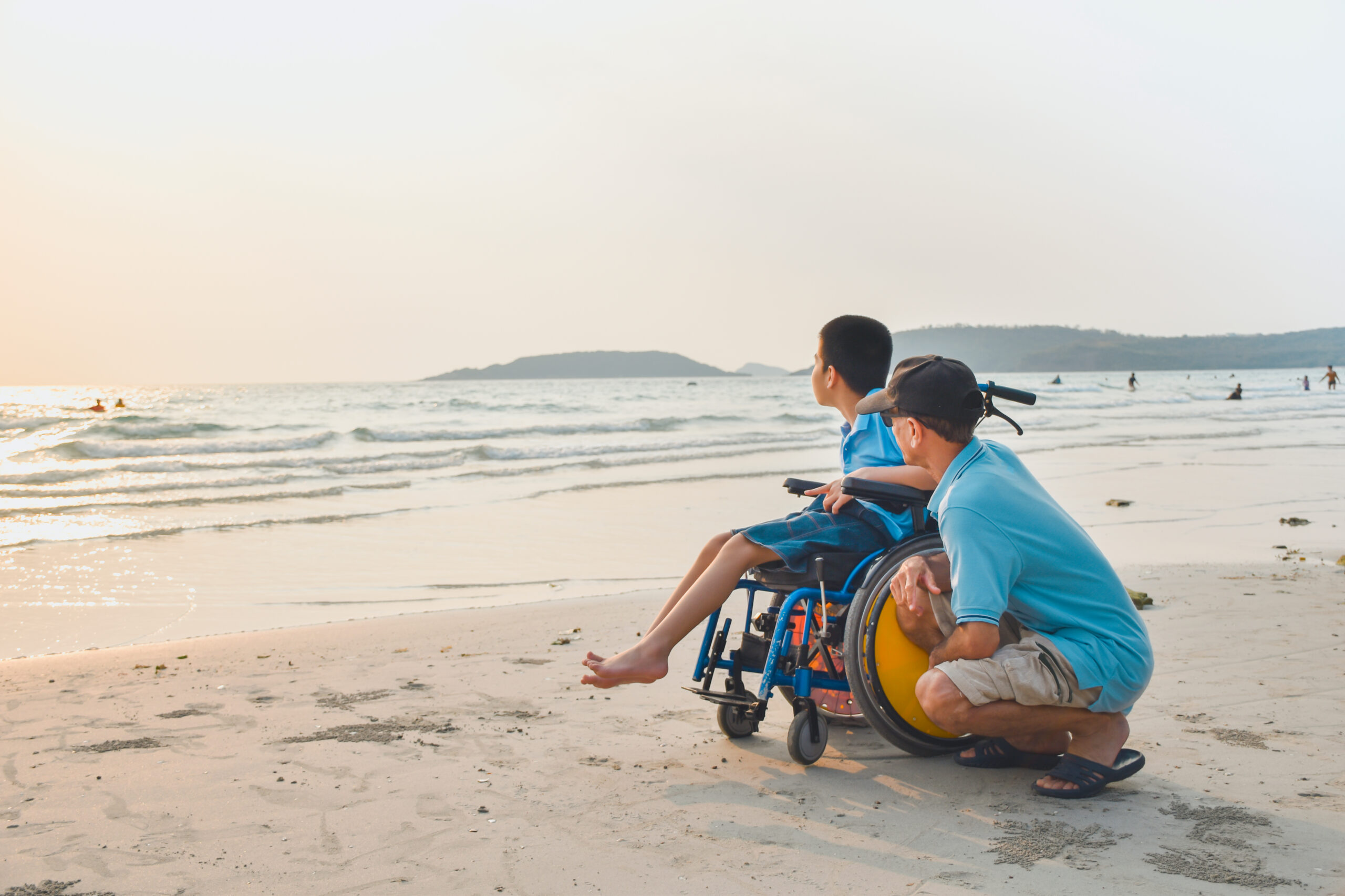 Special Needs Planning Services By Elite Estate Planning Boca Raton FL Asian special child on wheelchair and his dad on the beach at sunset, Father helped him to get closer to nature, Life in the education age of disabled children, Happy disabled kid concept.
