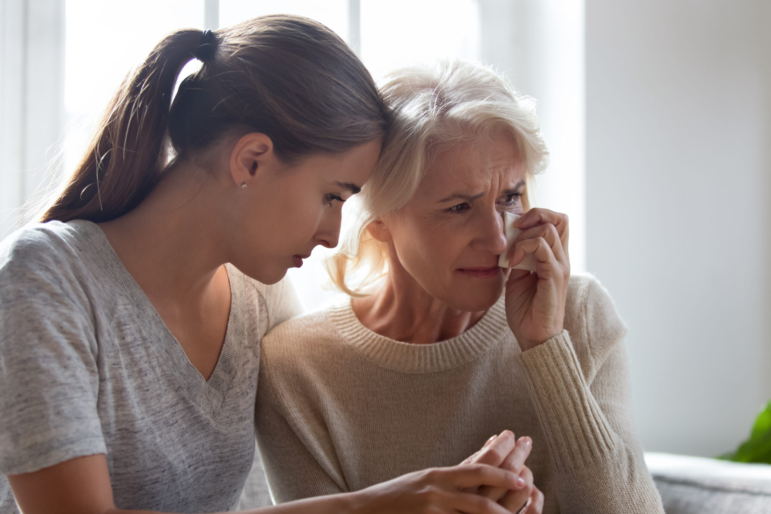 Trust Administration Elite Estate Planning Loving adult female hug comfort caress crying elderly mother wipe tears use paper tissue, show support and care, depressed desperate mom and daughter feel sad unhappy mourning for family loss